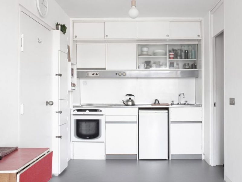 A cozinha é compacta e branca, o que ajuda a dar uma aparência luminosa e arejada